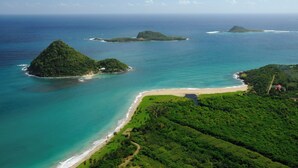 Une vue aérienne d’une zone côtière avec de nombreuses petites îles, une plage et une végétation luxuriante.