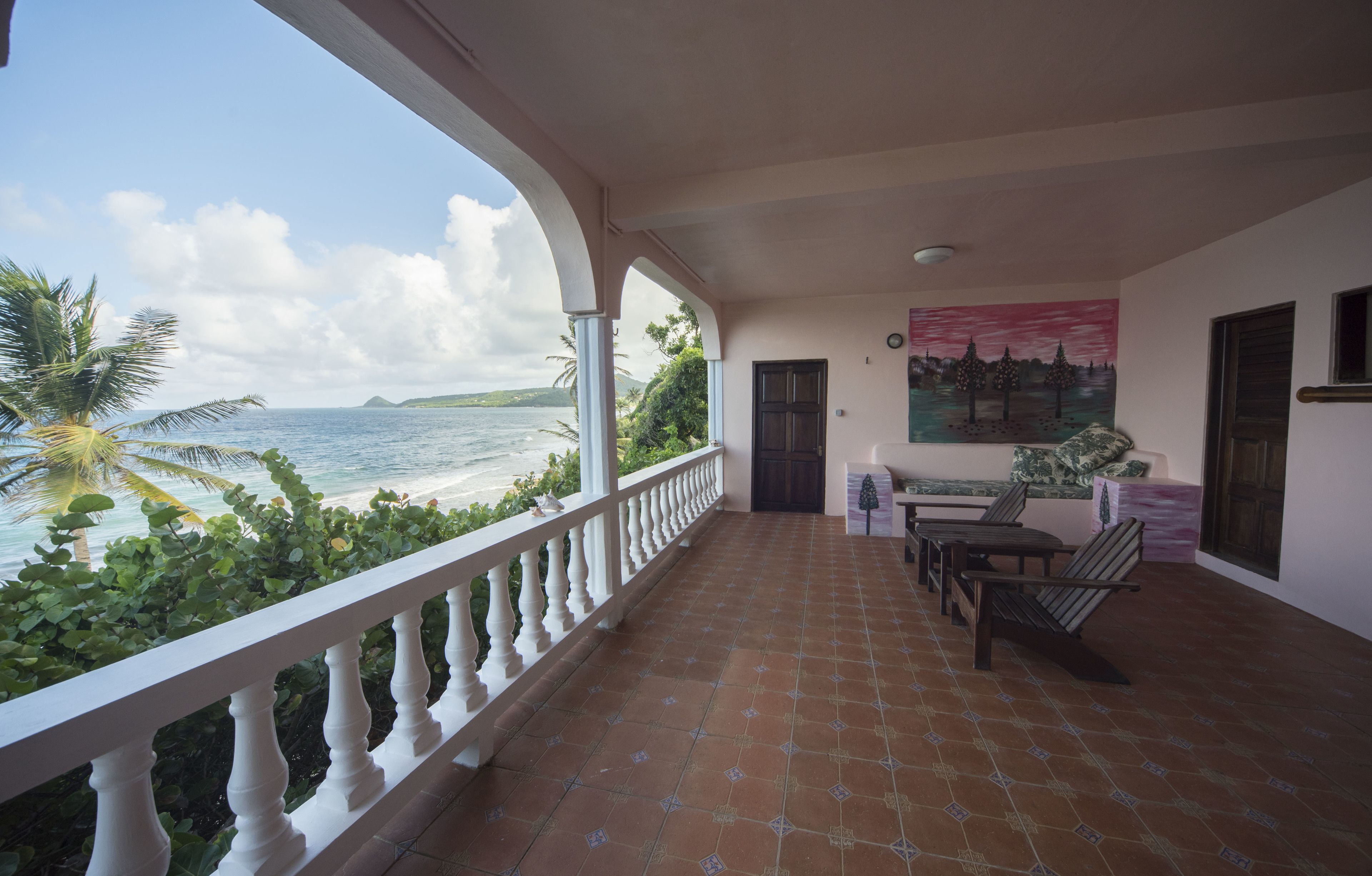 A balcony with a view of the sea, a table with chairs, and a door.