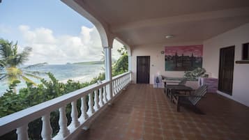 A balcony with a view of the sea, a table with chairs, and a door.