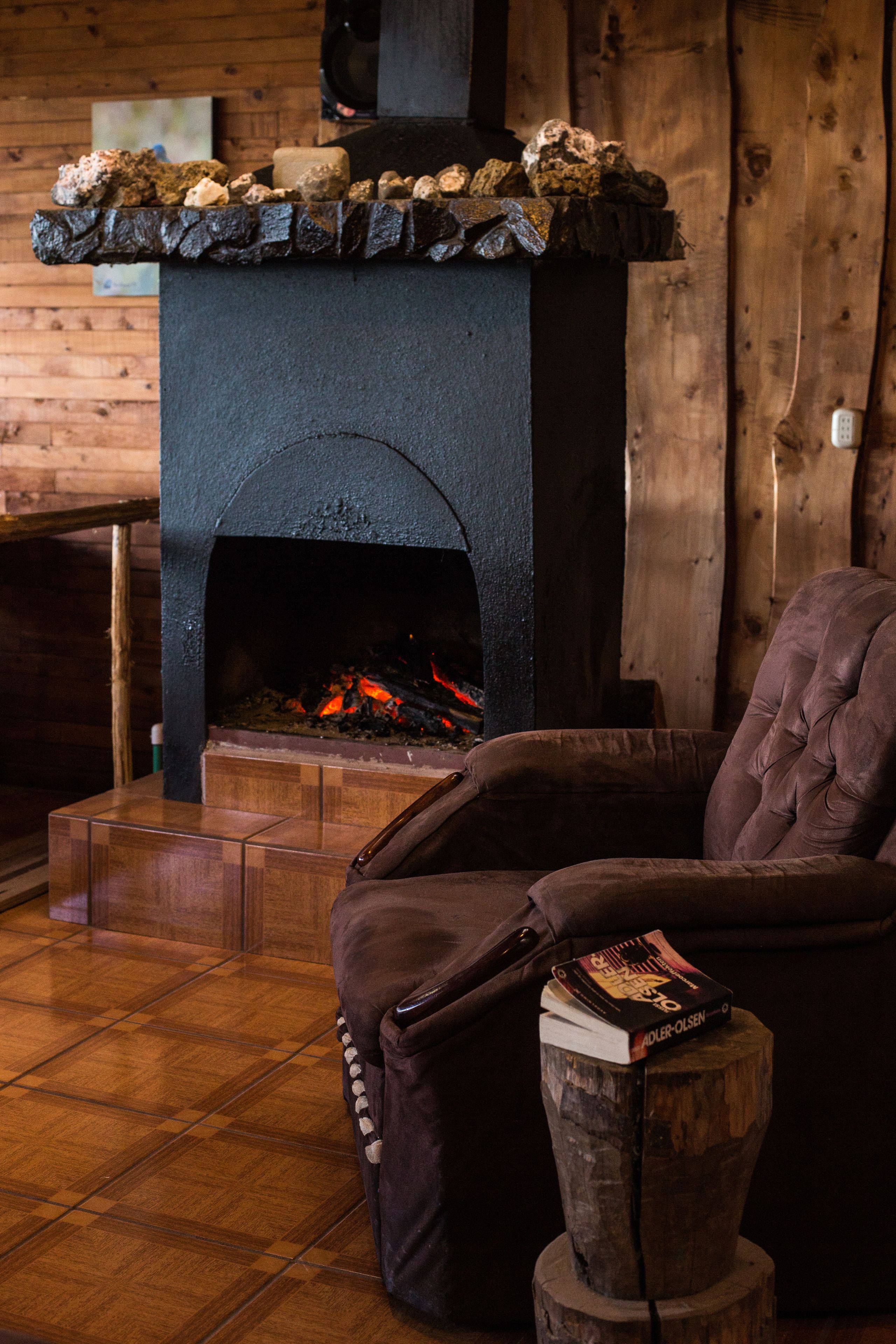 Una habitación acogedora con chimenea de piedra, una cama de madera y un sillón cómodo.