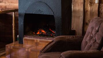 Una habitación acogedora con chimenea de piedra, una cama de madera y un sillón cómodo.