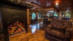 A cozy room with a fireplace, wooden flooring, and a plush armchair. - Paraíso Quetzal Lodge (Copey)