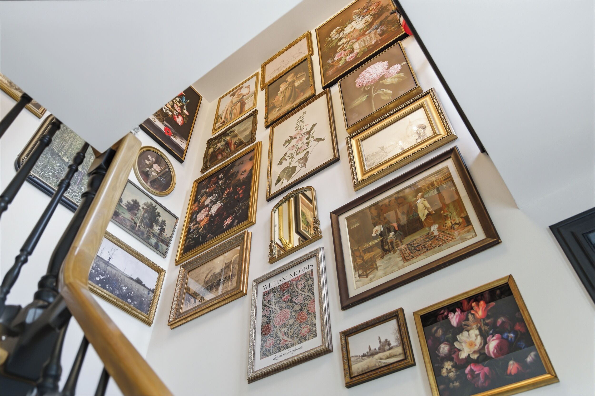 A wall with multiple framed artworks, including a William Morris piece.