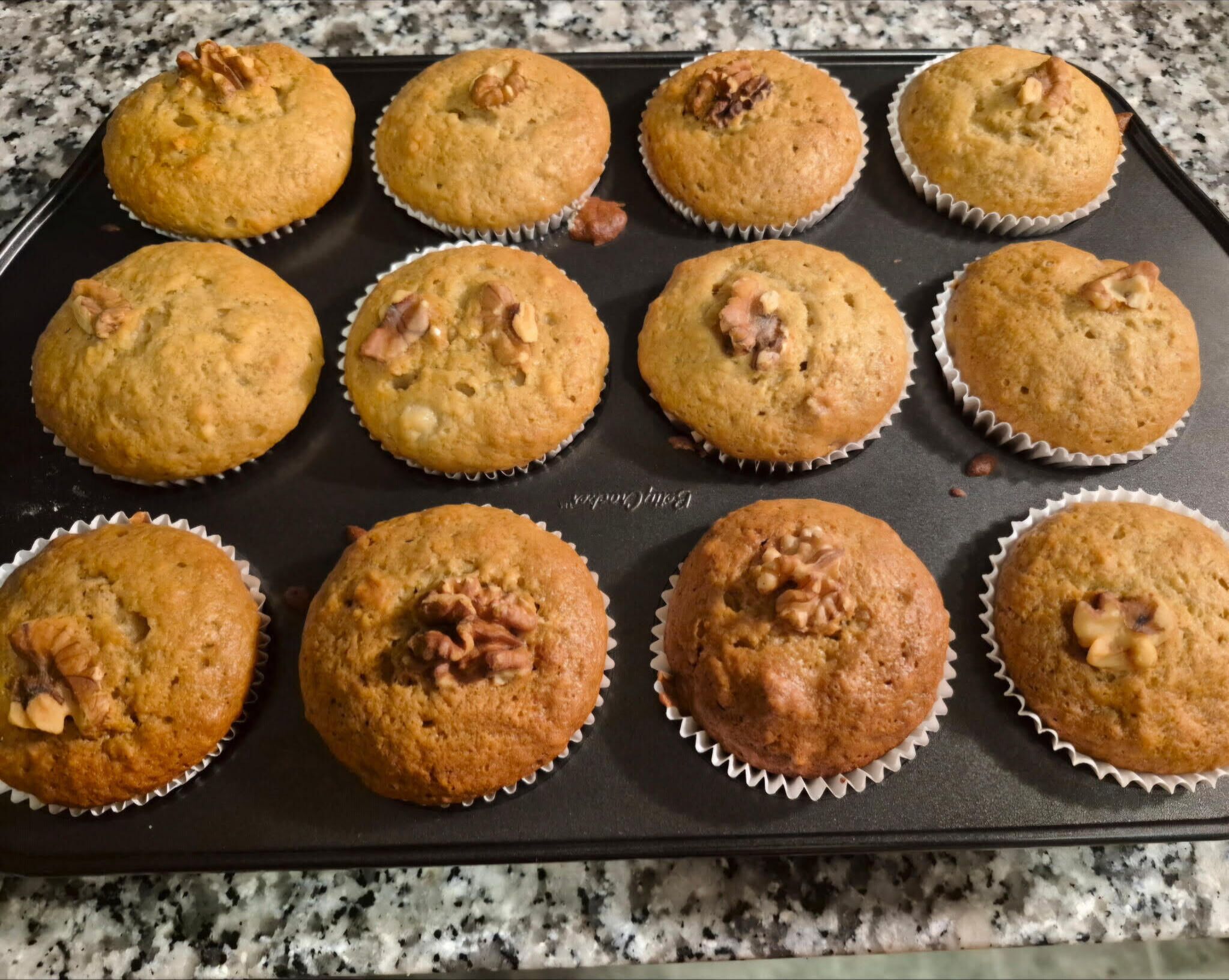 Una bandeja de muffins con nueces sobre una encimera de cocina.
