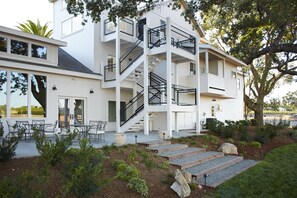 A multi-story building with a white exterior, outdoor seating area, and a landscaped garden. - SummerWood Winery & Inn (Paso Robles)