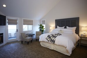A hotel room with a large bed, a small desk with a chair, a potted plant, and a fireplace. - SummerWood Winery & Inn (Paso Robles)