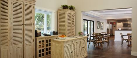 Una cocina amplia con armarios de madera, una isla central con frutero y un comedor con sillas.