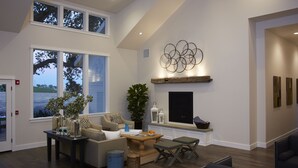 A spacious living room with a high ceiling, large windows, a fireplace, and a modern art piece on the wall. - SummerWood Winery & Inn (Paso Robles)