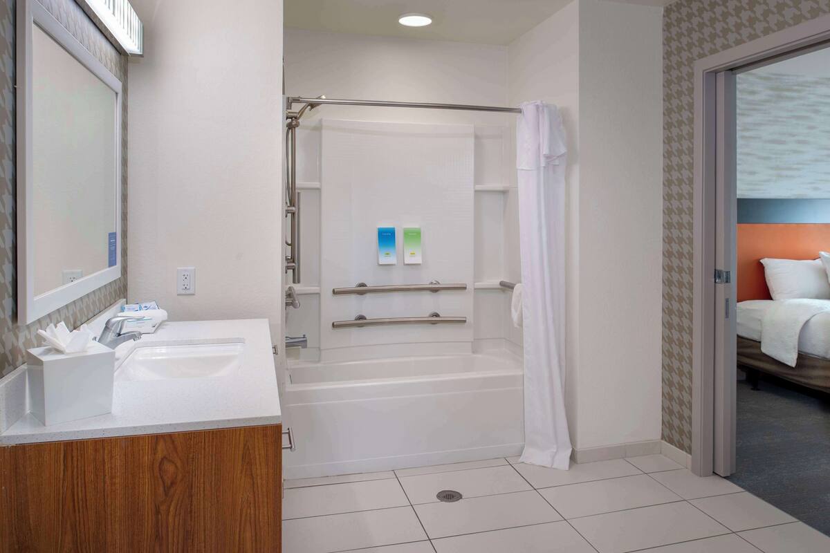 Un baño de hotel con bañera, ducha y lavamanos.