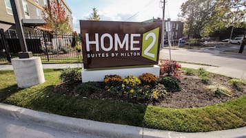 A sign for Home 2 Suites by Hilton with a landscaped garden in front.
