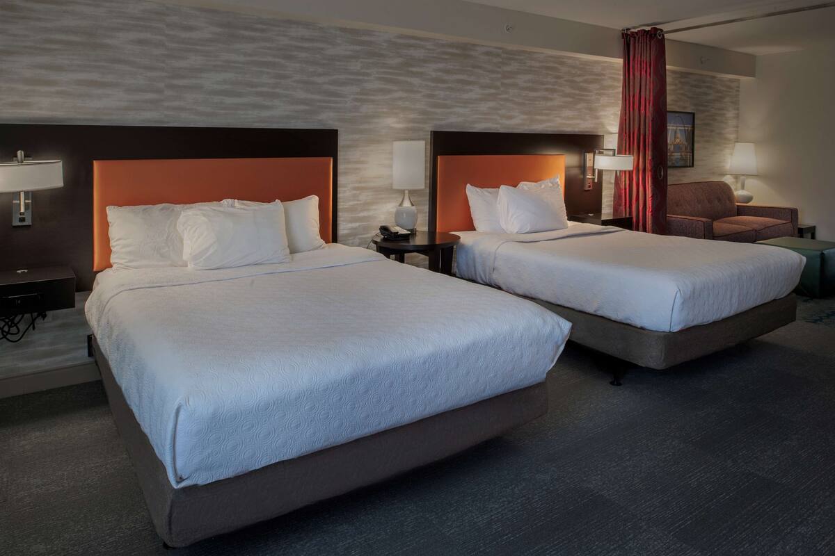 Habitación de hotel con dos camas, un sofá, un escritorio y una silla.