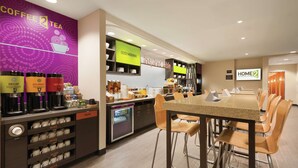 Ein Hotelcafé mit einer Kaffeemaschine, Tassen und einem Buffet.