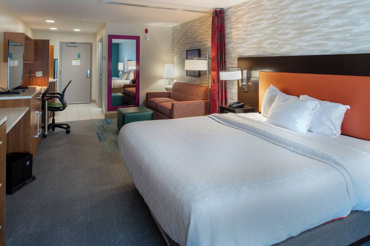 Una habitación de hotel con una cama grande, un escritorio, una silla y una mesita.