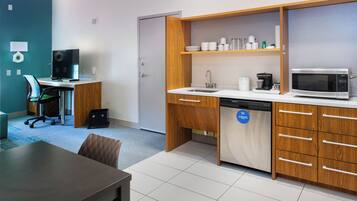 A compact kitchen with a microwave, sink, and wooden cabinets. There's a dining area with a table and chairs.