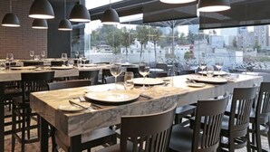 Un restaurante con mesas de mármol, sillas negras e iluminación colgante.