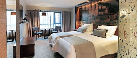 A hotel room with two beds, a desk, and a chair.