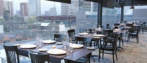 Un restaurante con vistas a la ciudad, muebles modernos y suelo estampado.