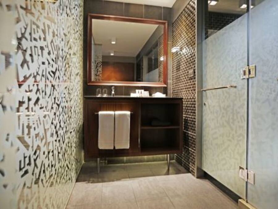 Une salle de bain moderne avec un grand miroir, un lavabo et un espace douche.
