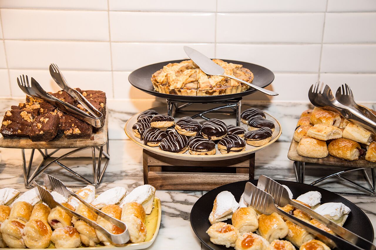 A variety of desserts on display, including brownies, chocolate-covered pastries, and pastries with powdered sugar.