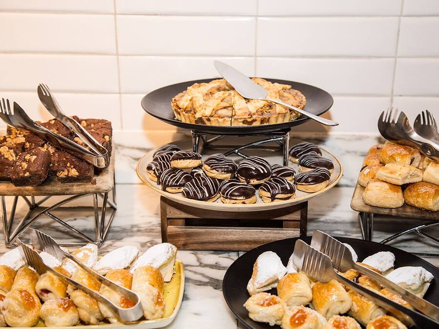 Variedad de postres a la vista, incluyendo brownies, pastas bañadas en chocolate y pastas espolvoreadas con azúcar glas.