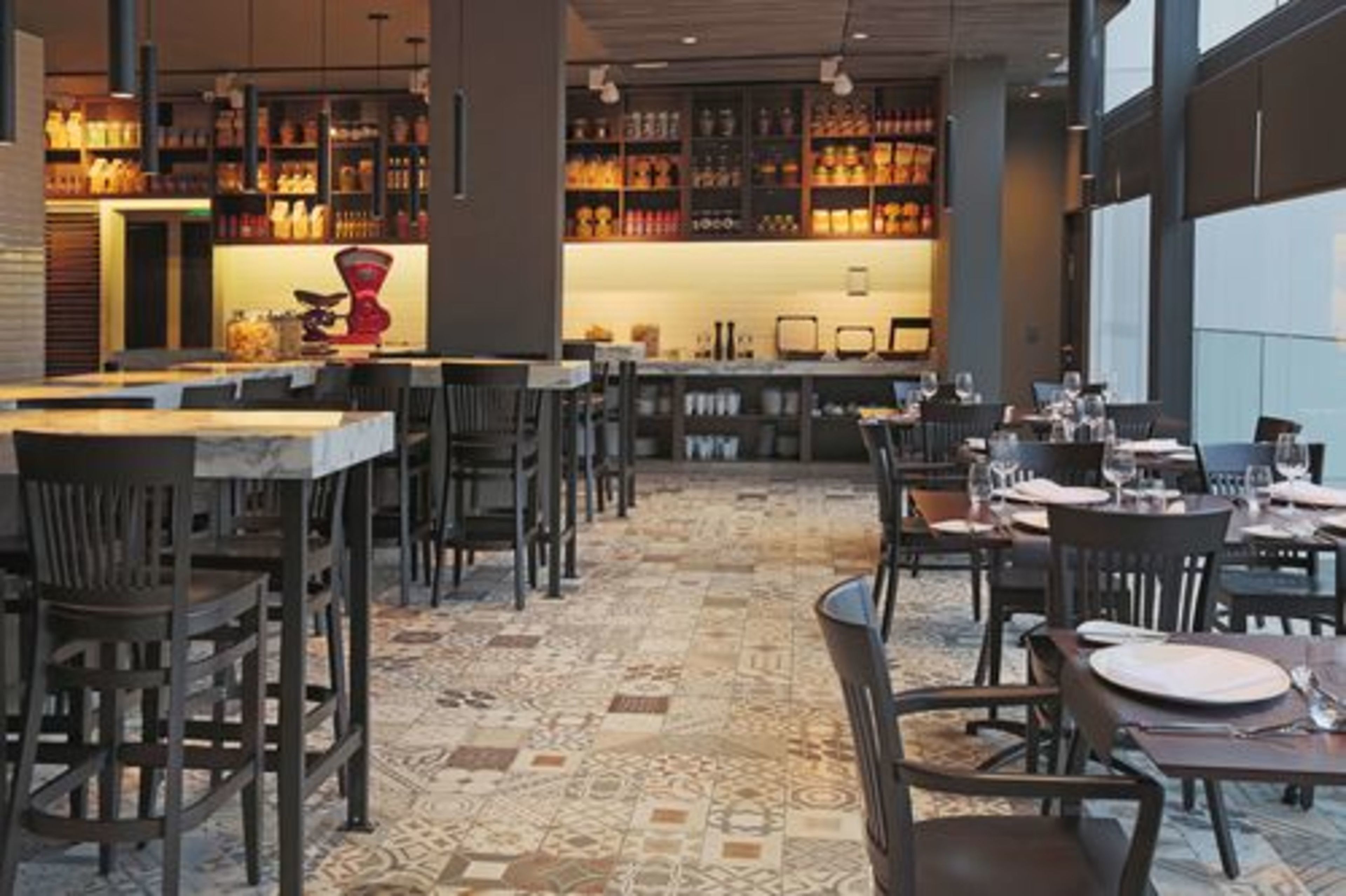 A restaurant with a patterned floor, dark wooden chairs, and tables set for dining.