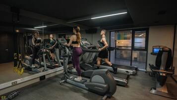 Un gimnasio con cintas de correr, un espejo y una ventana con vistas.