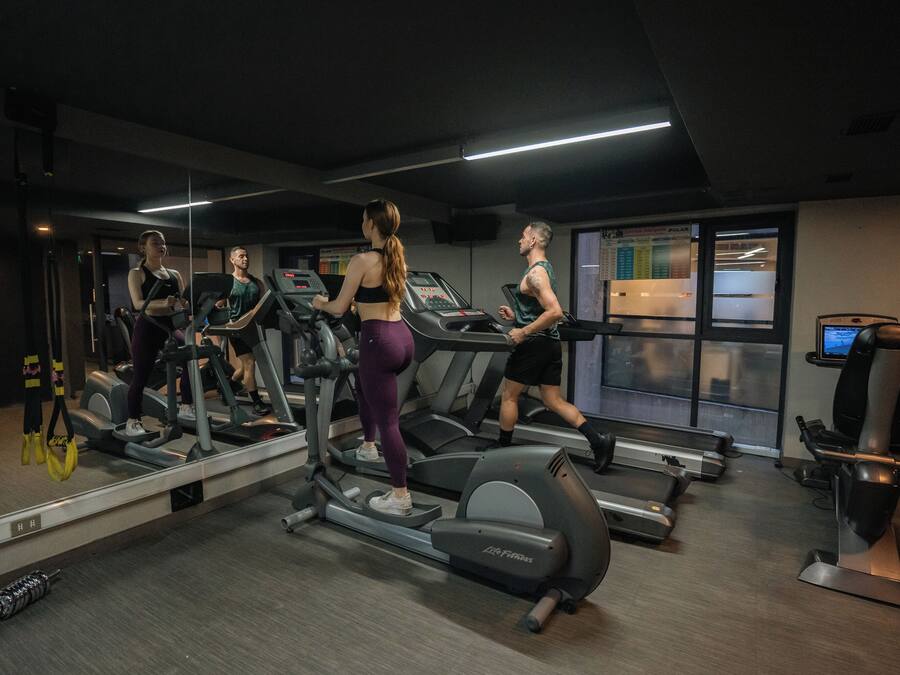 Un gimnasio con cintas de correr, un espejo y una ventana con vistas.