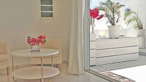 Una habitación moderna con una mesa redonda blanca, un sofá y vistas a un balcón con plantas en macetas.