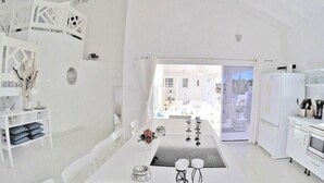 Una cocina moderna con armarios blancos, un comedor con mesa y sillas, y vistas al exterior.