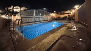A rooftop swimming pool with a checkered pattern, surrounded by lounge chairs and a covered seating area. - Riad Dar Tahri & SPA (Fes)