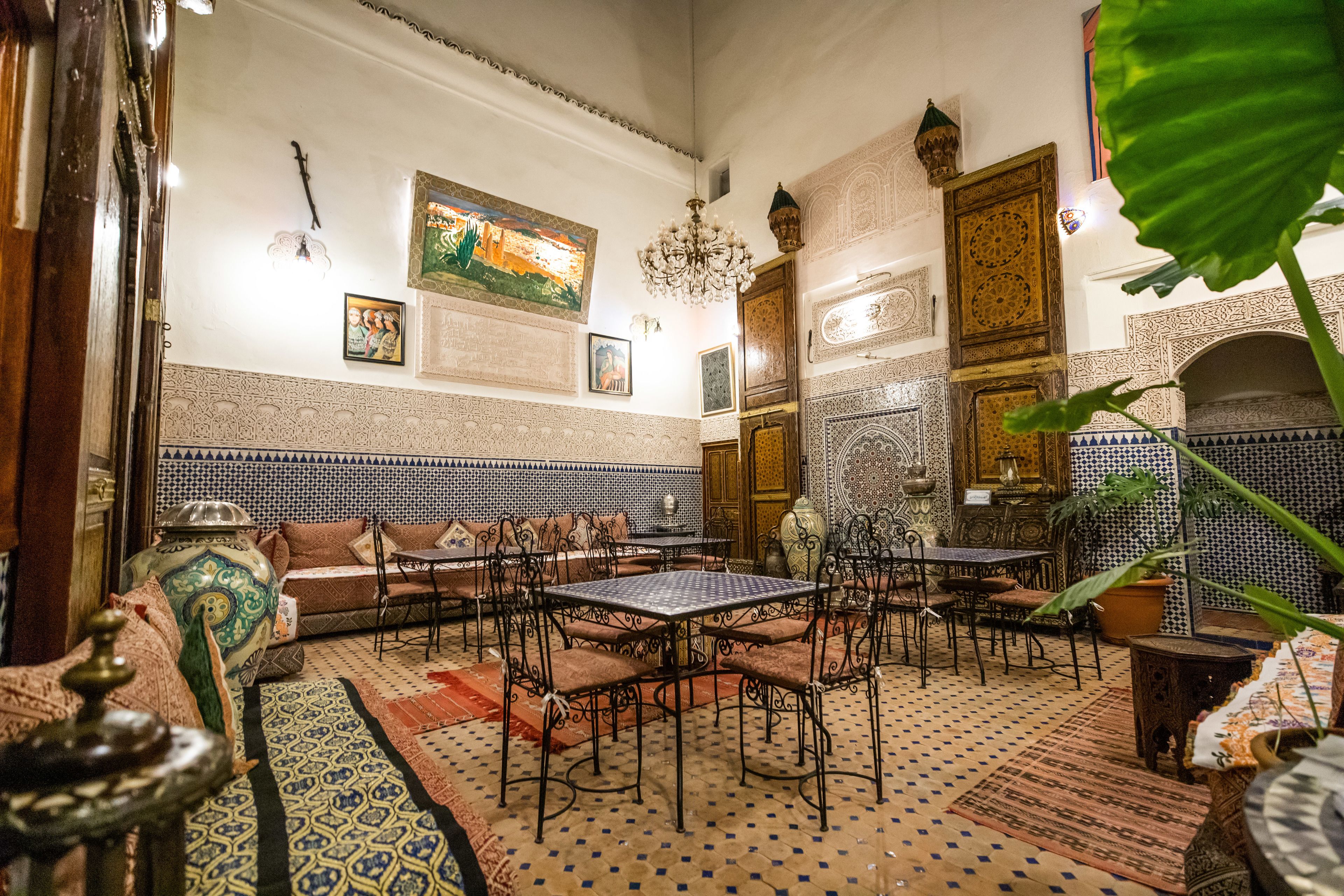 A traditional Moroccan interior with patterned tiles, ornate furniture, and a chandelier.