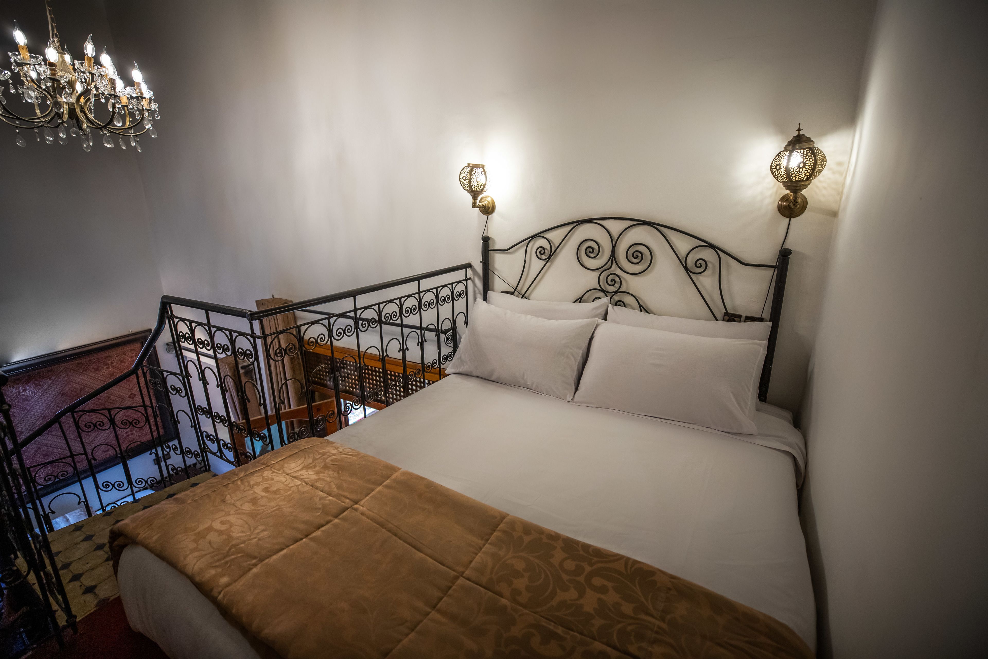 Un dormitorio con cama, candelabro y escalera.