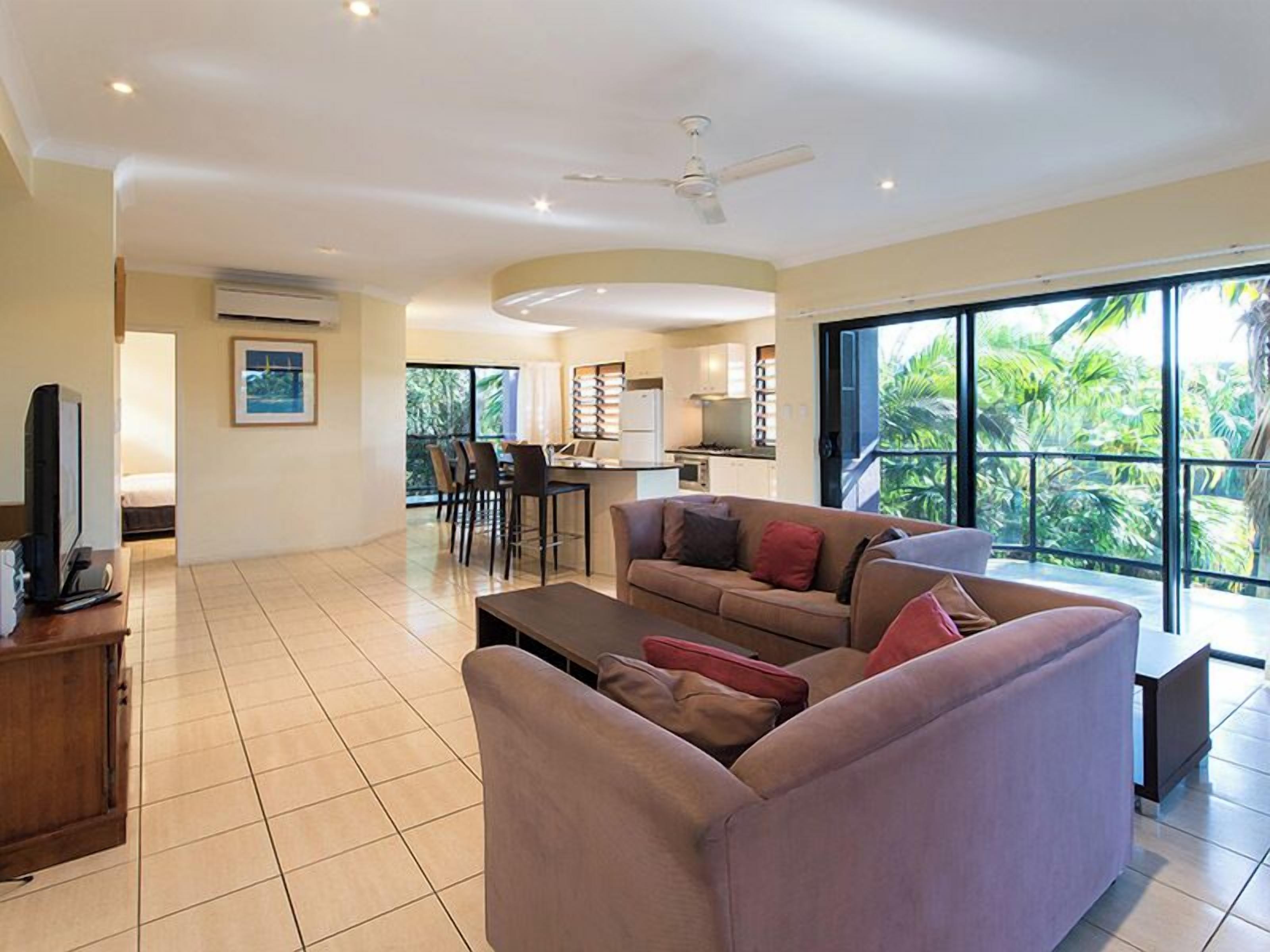 A spacious living area with a sofa, a TV, and a dining area with chairs and a table.