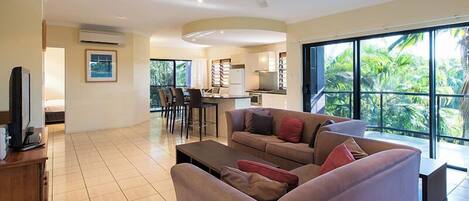 A spacious living area with a sofa, a TV, and a dining area with chairs and a table.