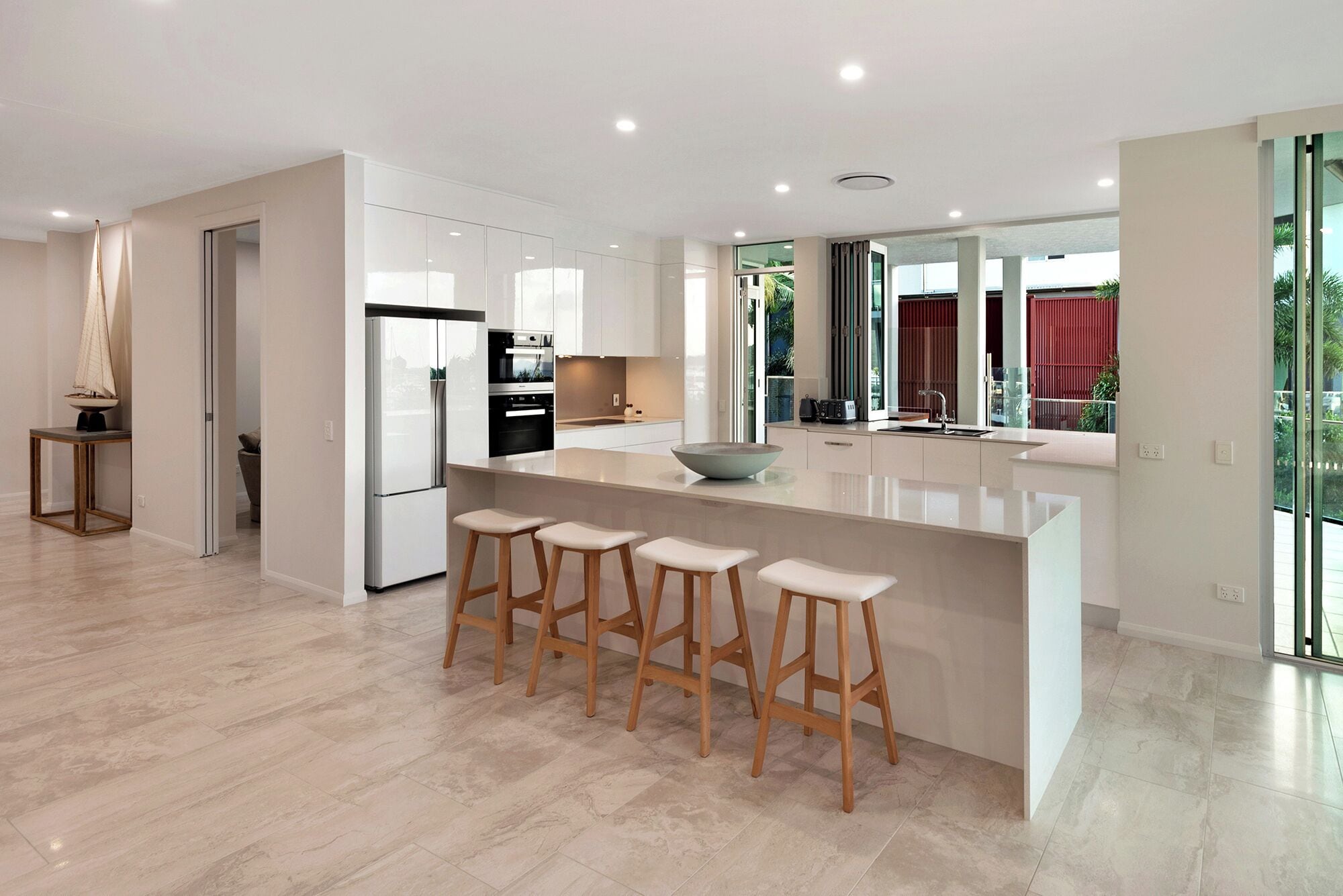 A modern kitchen with a large island, bar stools, and a built-in oven.