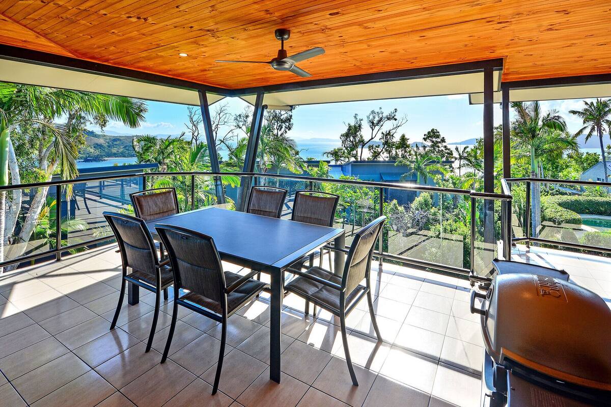 A spacious outdoor dining area with a wooden ceiling and a view of the ocean.
