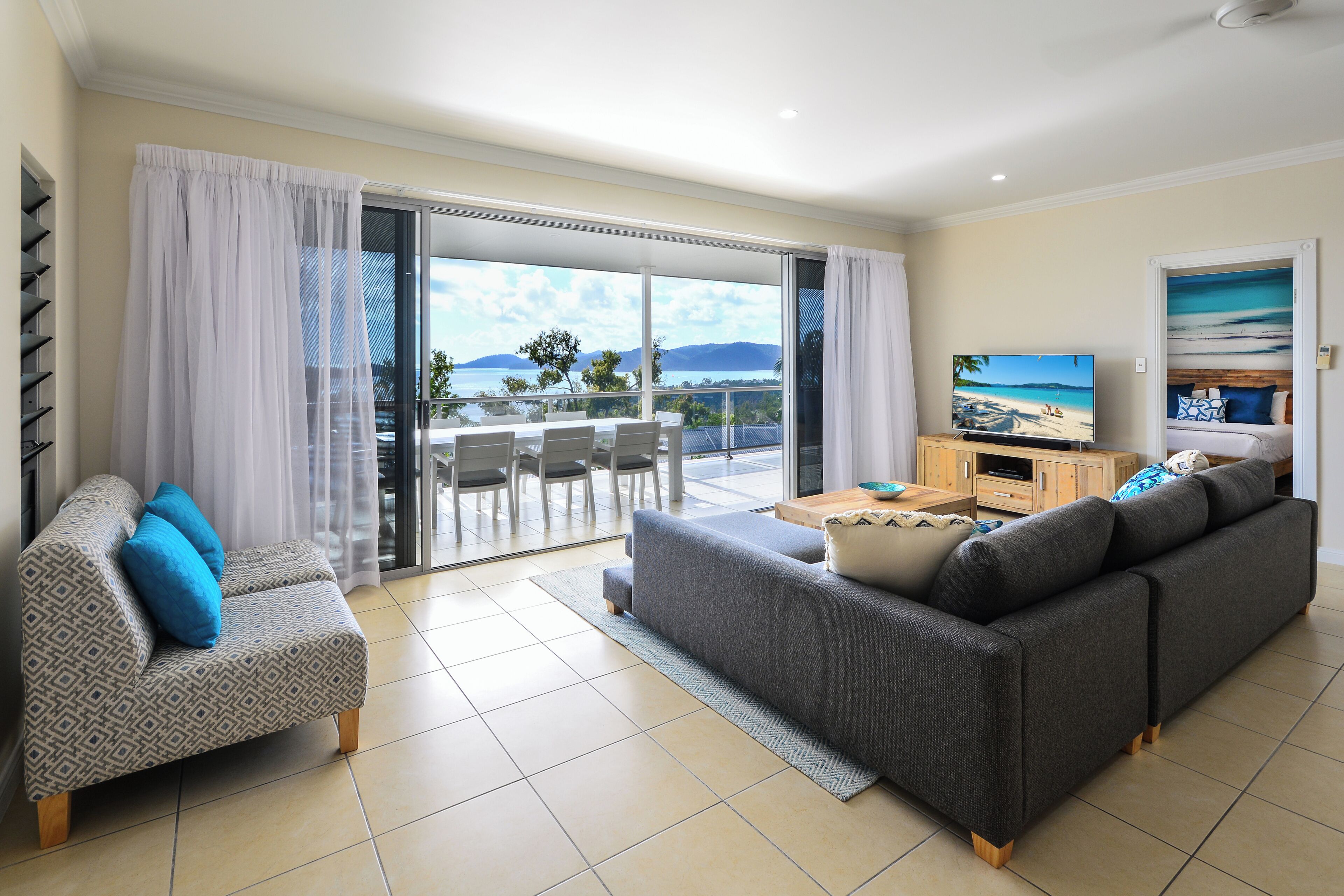 Un salon avec un canapé, un fauteuil, une télévision et un balcon offrant une vue agréable.