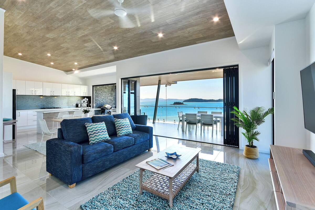 A modern living room with a sofa, coffee table, and a view of the sea.