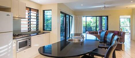 A modern kitchen with a central island, a dining area with chairs, and a sofa.