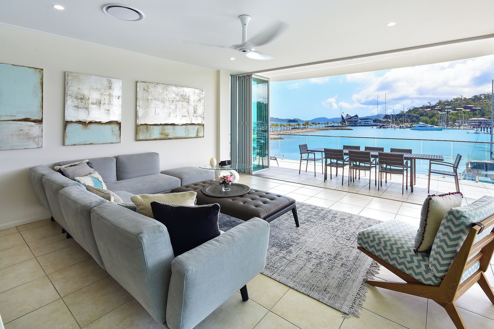 A modern living room with a sofa, ottoman, and a dining area with chairs and a table.