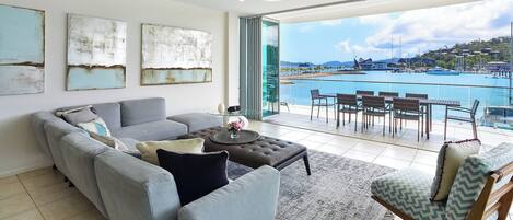 A modern living room with a sofa, ottoman, and a dining area with chairs and a table.