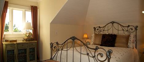 A bedroom with a bed, a bench, a dresser, and a window with curtains.