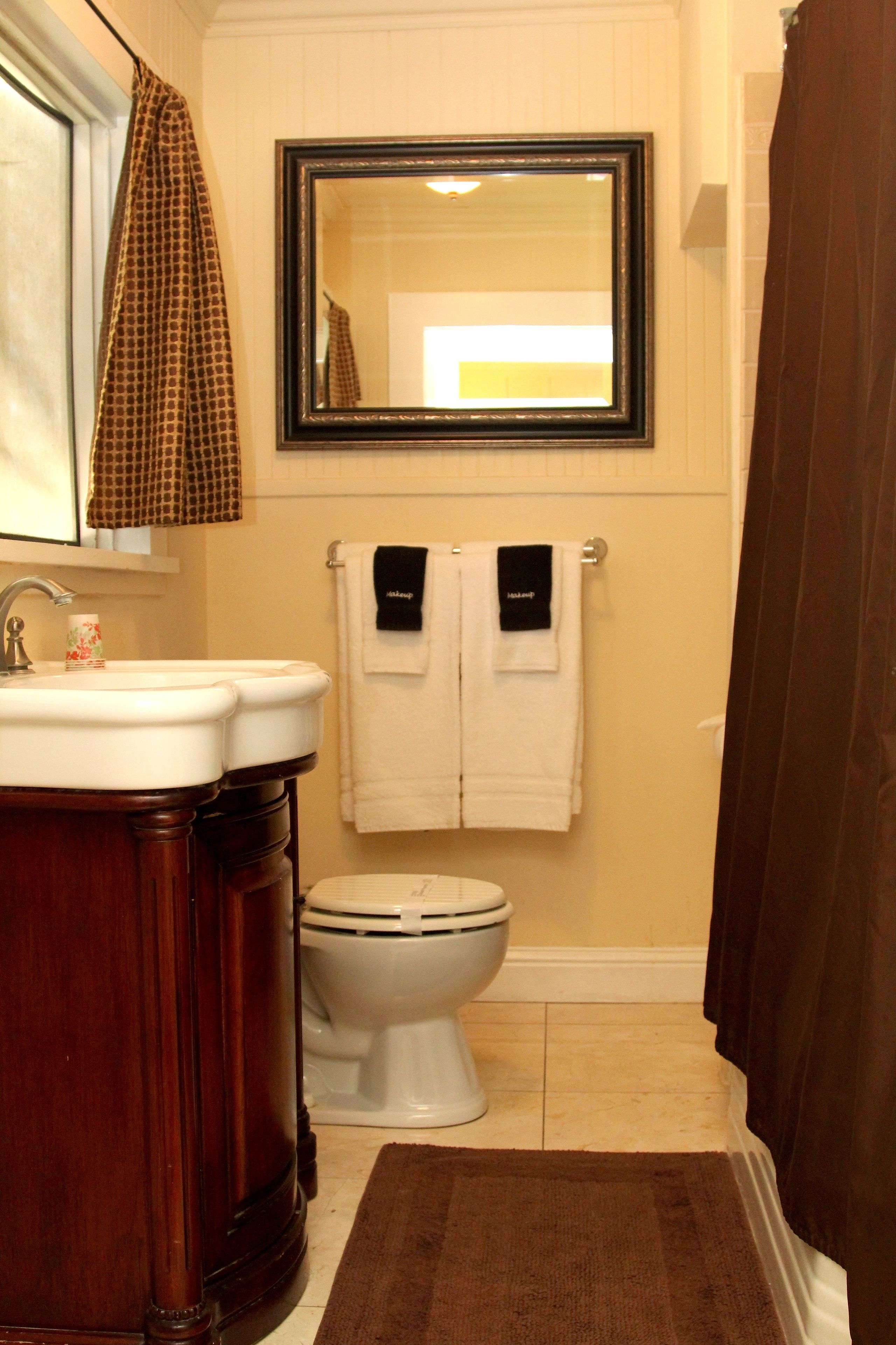 A bathroom with a wooden vanity, a white sink, a toilet, and a mirror above the mirror.
