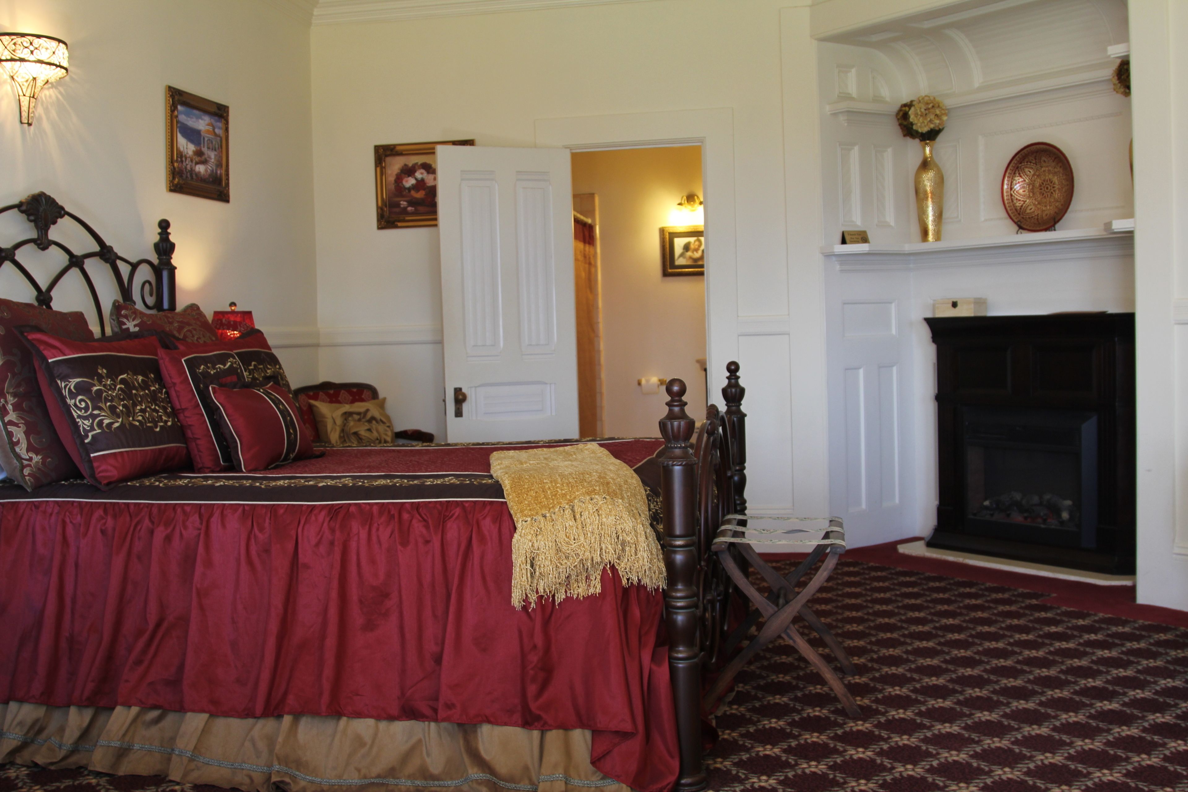 Un dormitorio tradicional con una cama grande, una chimenea y un pasillo que conduce a otra habitación.