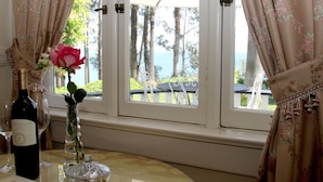 A table with a wine bottle, a glass, and a vase with a flower. - Monarch Cove Inn (Capitola)
