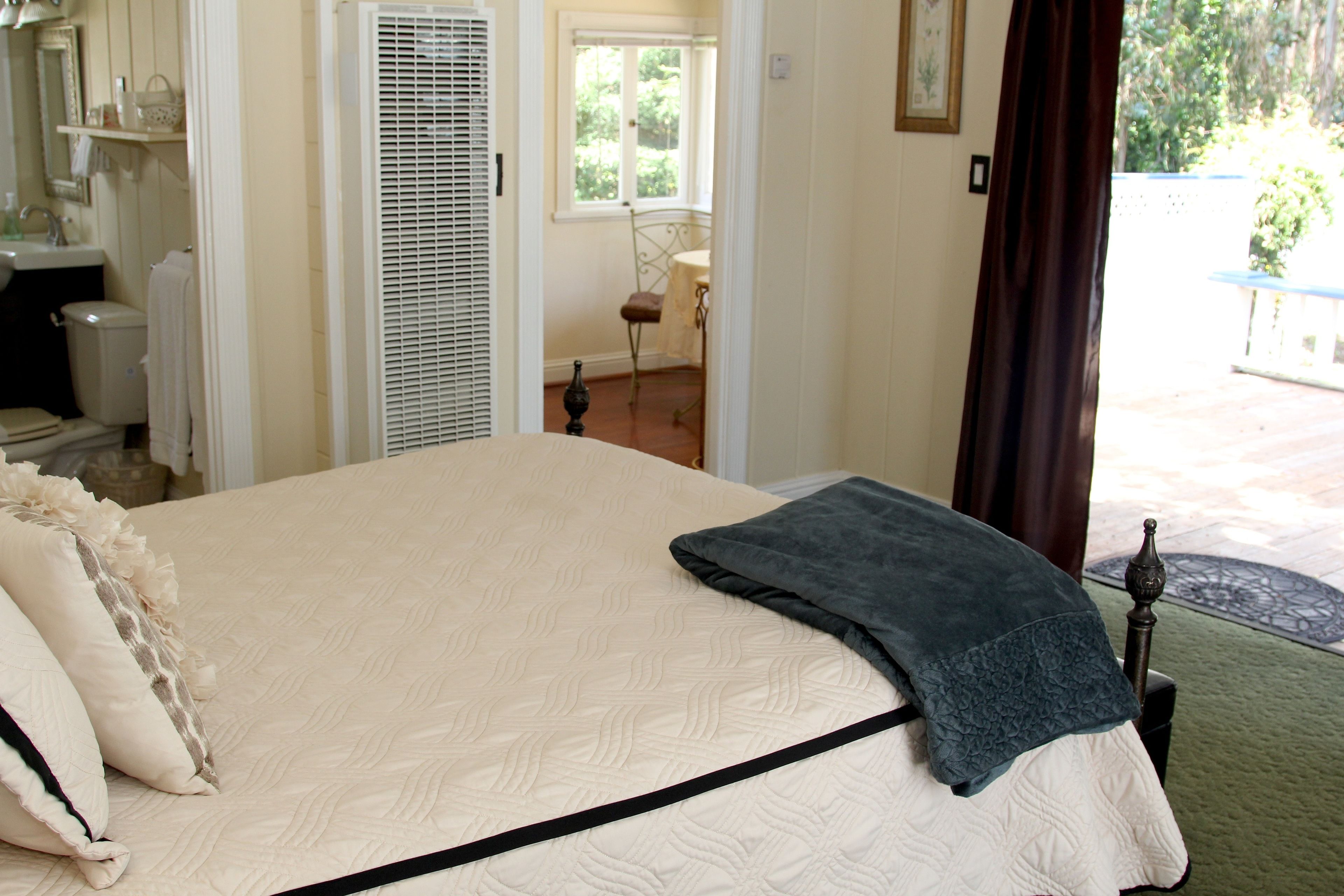 Un dormitorio con cama, ventana, puerta y vista al exterior.