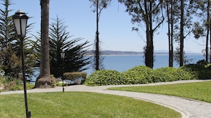 A landscaped pathway with a view of the sea, surrounded by trees and a lamp post. - Monarch Cove Inn (Capitola)