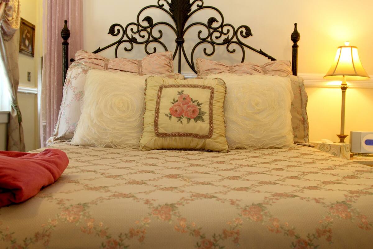 A neatly made bed with floral bedding and a decorative headboard.