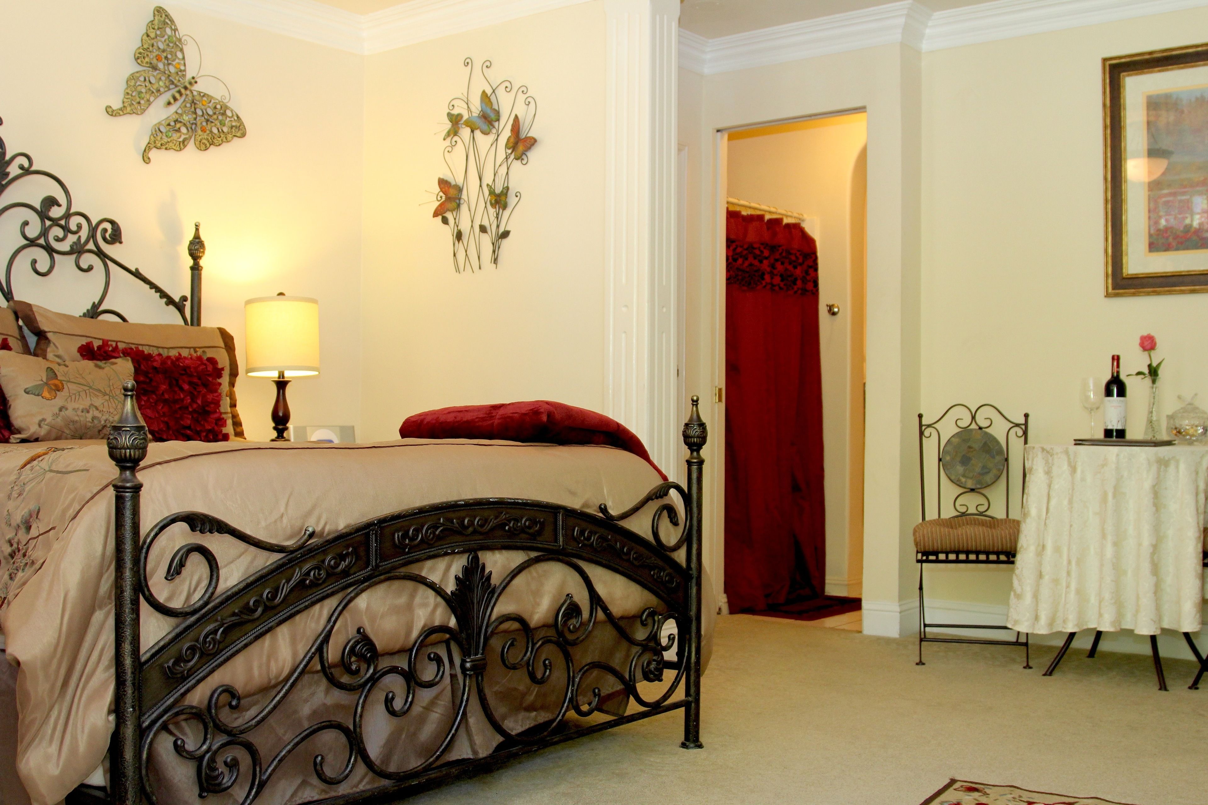 Een slaapkamer met een bed, nachtkastje, lamp, stoel, tafel en een deur.