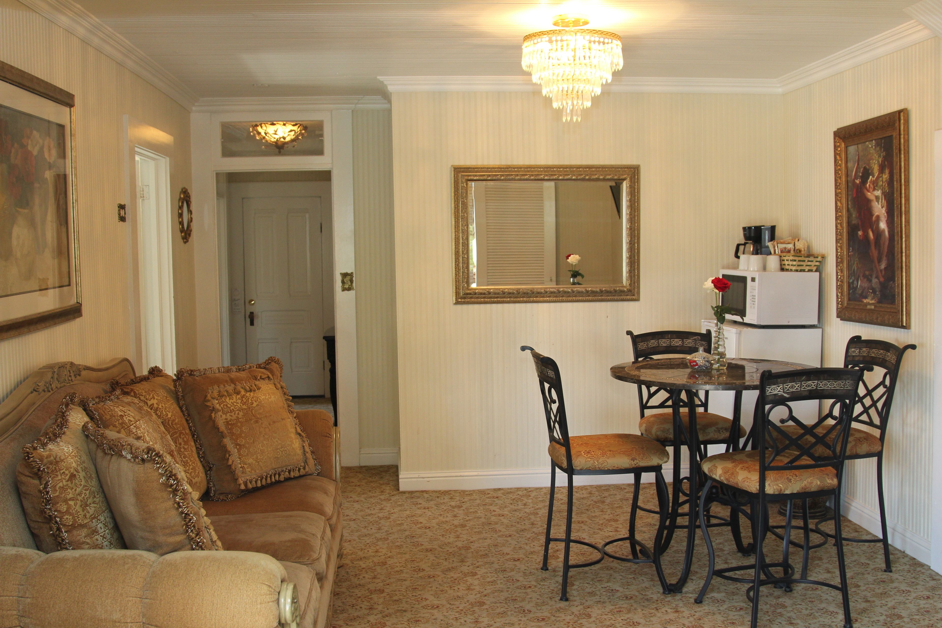 A dining area with a round table and chairs, a chandelier, and a mirror on the wall.